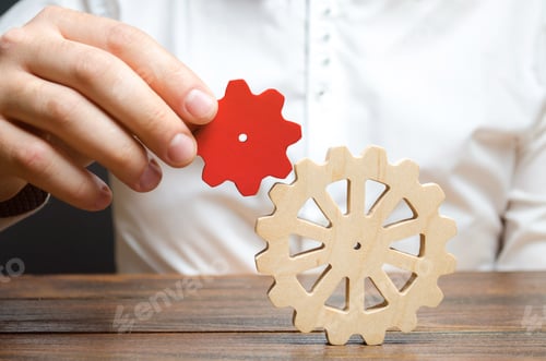 Preview: Businessman connects a small red gear to a large gear wheel.