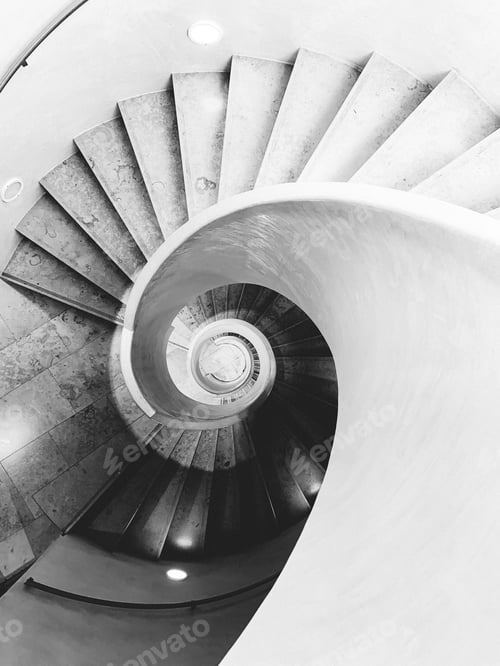 Preview: High-angle shot of round stairs in black and white.