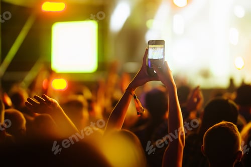 Preview: Hand with a phone records live music festival. People taking photographs with smart phone.