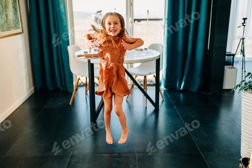Preview: Little kid happy girl dancing on the kitchen at cozy home lifestyle authentic moment