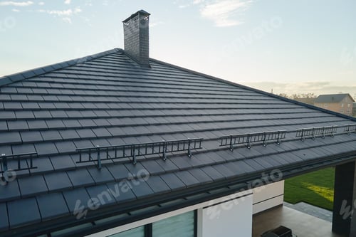 Preview: Closeup snow guard for safety in winter on house roof top covered with ceramic shingles