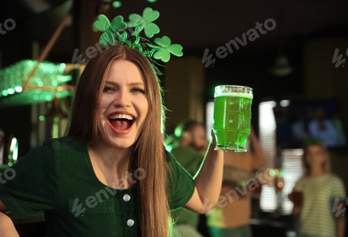 Preview: Young woman with glass of green beer in pub. St. Patrick's Day celebration