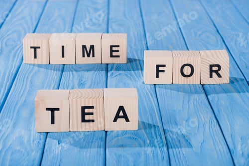 Visualização: vista de perto de blocos de madeira dispostos a tempo para uma frase de chá na superfície de madeira azul