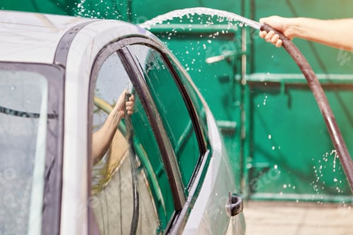 Preview: Man washing automobile with water with the hose