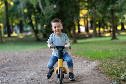 Preview: A cute smiling toddler boy of three or four years old rides a bicycle