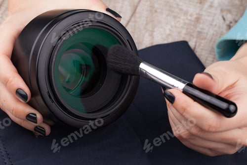Preview: The photographer cleans the lens of dust on a wooden table