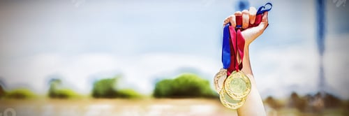 Preview: Hand of female athlete holding gold medals