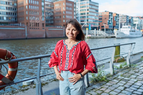 Preview: Mature smiling woman in embroidered shirt looking at camera, outdoor
