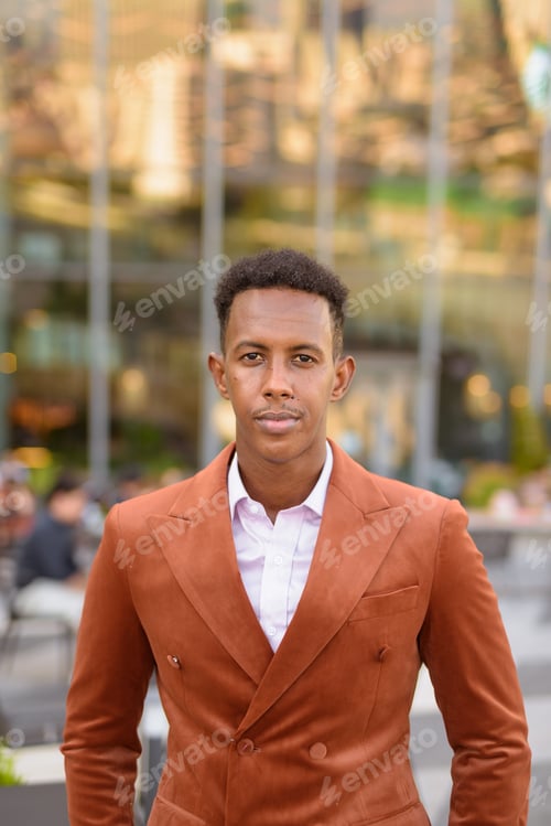 Preview: Portrait of handsome black African businessman outdoors in city