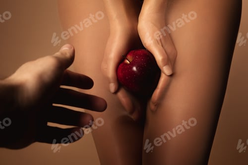 Preview: cropped view of man reaching woman in nylon tights holding ripe red apple isolated on brown