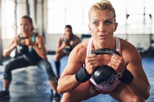 Preview: Burning fat and building muscles. Shot of a group of people lifting weights at the gym.