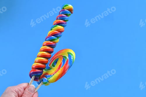 Preview: Holding colorful giant lollipops against a sky blue background. colors, swirl, swirly