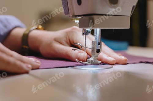 Preview: woman sews piece of cloth on sewing machine. industrial metal machine for all fabric tops.