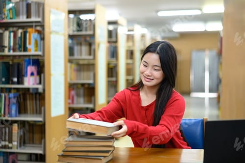 Preview: Asian student organizing books in library with cheerful and focused attitude