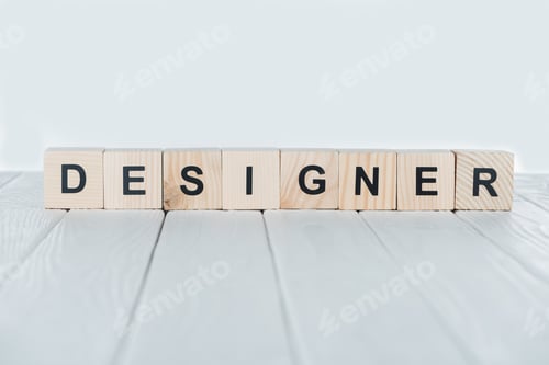 Preview: close up view of designer word made of wooden cubes on white wooden tabletop