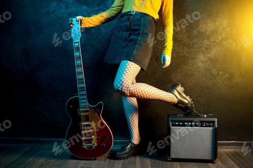 Preview: Close-up photo of young hipster woman legs and red guitar in neon lights.