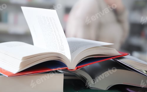 Preview: stack of books on the table. open book
