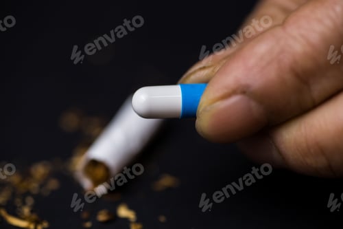 Preview: Closeup shot of a person holding a medicine capsule in front of a black background