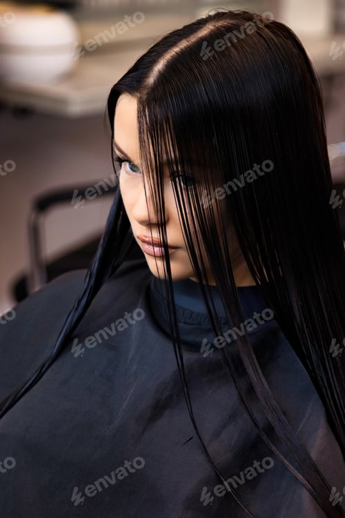 Preview: Portrait of lovely brunette lady sitting on barber chair in hair salon, pensive look