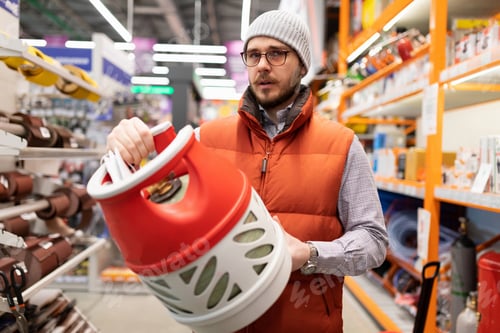 Preview: a man chooses a gas cylinder made of plastic to store propane
