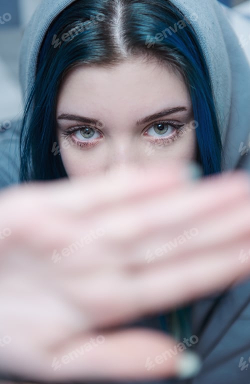 Preview: A teenage girl with blue hair covers her face with her hand