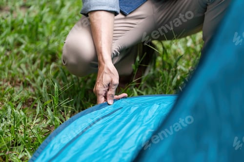 Preview: Family camping experience. Close-up of hands setting up a tent.