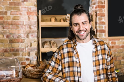 Preview: Handsome seller smiling and standing in bakery
