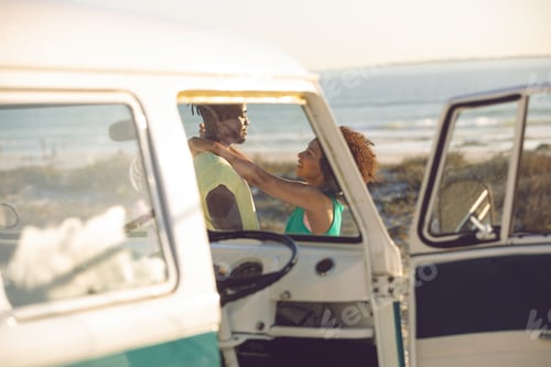 Preview: Side view of romantic Caucasian couple embracing each other near camper van at beach