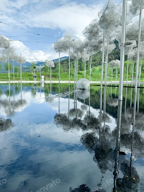 Preview: Swarovski museum outdoor installation reflecting on water with snowcapped mountains in the backgroun