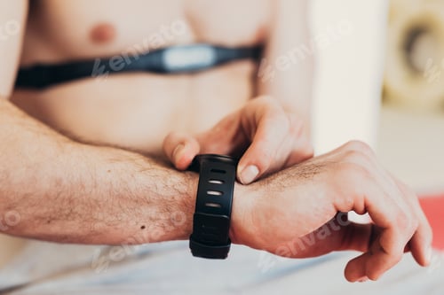 Preview: Man wearing heart rate monitor on chest checking wrist watch