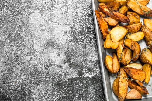 Preview: Fried potatoes on a baking tray with spices and herbs.