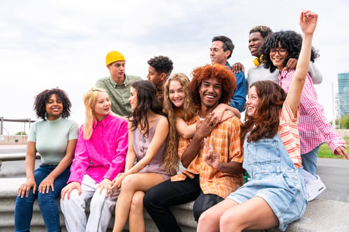 Preview: Happy playful multiethnic group of young friends bonding outdoors