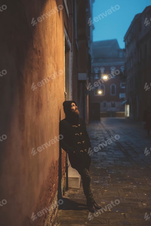 Preview: Portrait of man leaning against street wall at dusk, Venice, Italy
