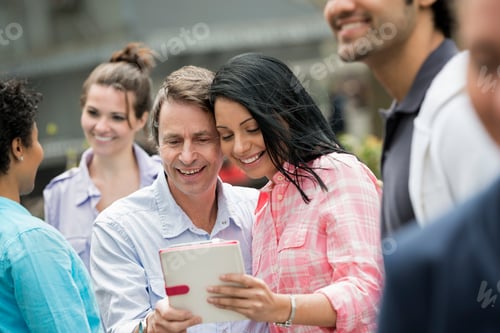 Preview: A group of men and women,a couple looking at a digital tablet screen.