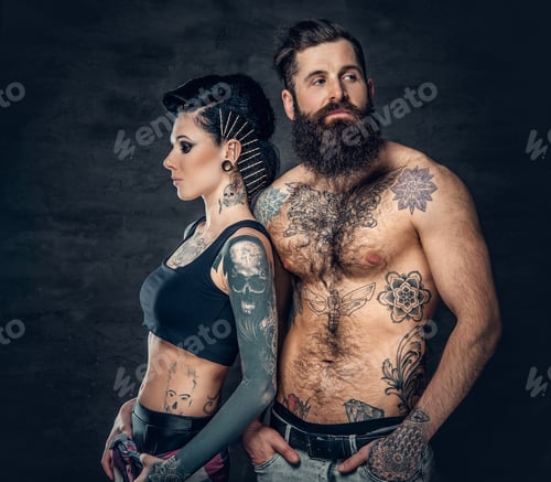 Preview: Portrait of shirtless, tattooed bearded male and brunette female with tattoo ink on her torso.