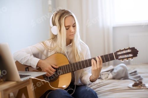 Preview: Woman Plays Guitar and Listens with Headphones