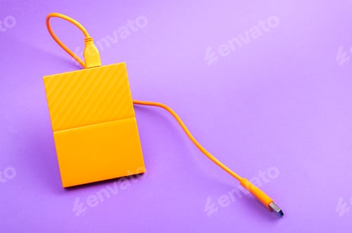 Preview: Orange color external portable hard disk drives isolated on light purple background