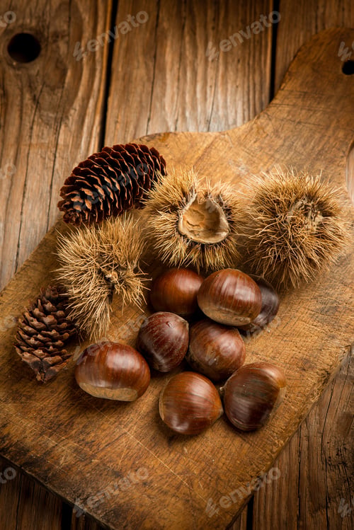 Preview: raw chestnuts with hedgehog over wooden table