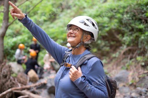 Preview: Smiling senior hiker woman wearing helmet in a trekking mountain day