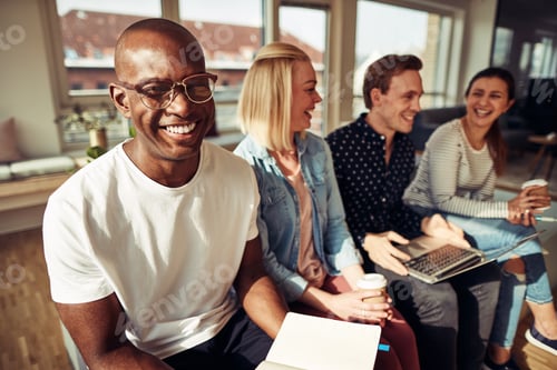 Preview: Smiling African businessman sitting with coworkers in a modern office