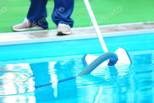 Preview: Male worker cleaning outdoor pool with underwater vacuum
