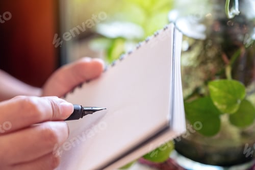 Preview: A woman holding and writing on notebook by fountain pen