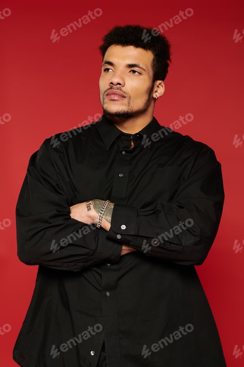 Preview: Young handsome man poses confidently in stylish black attire against a vibrant red background