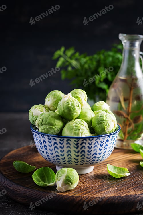 Preview: Fresh organic brussels sprouts in a bowl on a dark background. Healthy food. Vegan/vegetarian meal.