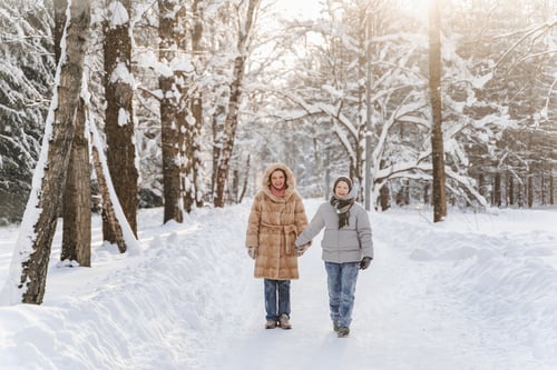 Preview: Walking mother with teen son on snowy forest road, tall trees, calm winter landscape, family time