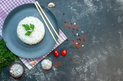 Preview: Top view of delicious rice meal served with green wooden chopstics on a black plate on purple