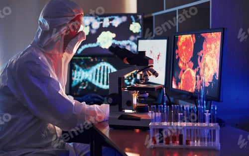 Preview: Scientist in white protective uniform works with coronavirus and blood tubes in laboratory