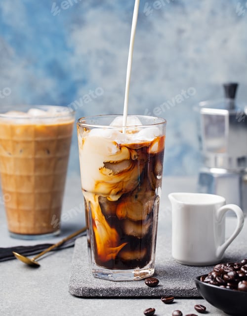 Preview: Ice coffee in a tall glass with cream poured over and coffee beans on a grey stone background