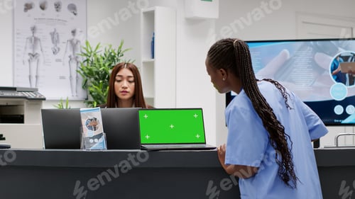 Preview: Nurse working at reception counter desk with greenscreen on laptop