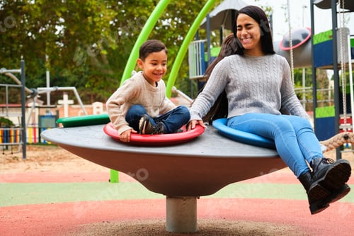 Preview: Lesbian couple laughing while playing with their son in the playground.